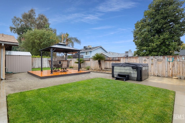 view of yard featuring a storage shed, a hot tub, a fenced backyard, a gazebo, and an outdoor structure