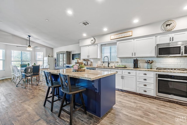 kitchen featuring lofted ceiling, sink, a center island, appliances with stainless steel finishes, and white cabinets