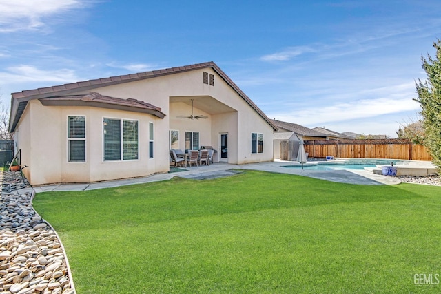 back of house featuring a fenced in pool, a yard, and ceiling fan