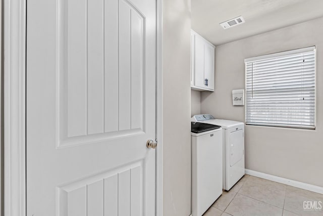 washroom featuring light tile patterned flooring, washing machine and clothes dryer, and cabinets