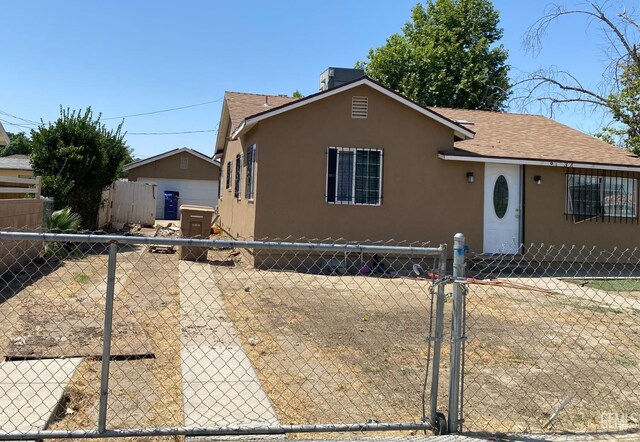 1231 6th St, Bakersfield, CA 93304 - view of front of house featuring stucco siding, a shingled roof, and a gate