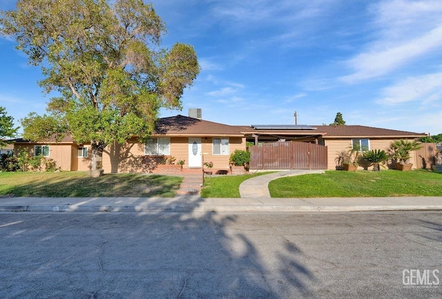 single story home featuring a gate, roof mounted solar panels, fence, and a front lawn
