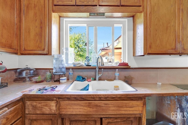 kitchen with brown cabinetry, a sink, and light countertops