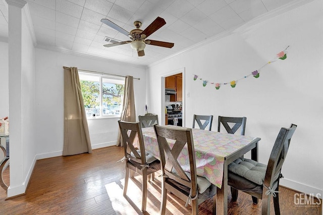 dining space featuring wood finished floors, crown molding, baseboards, and a ceiling fan