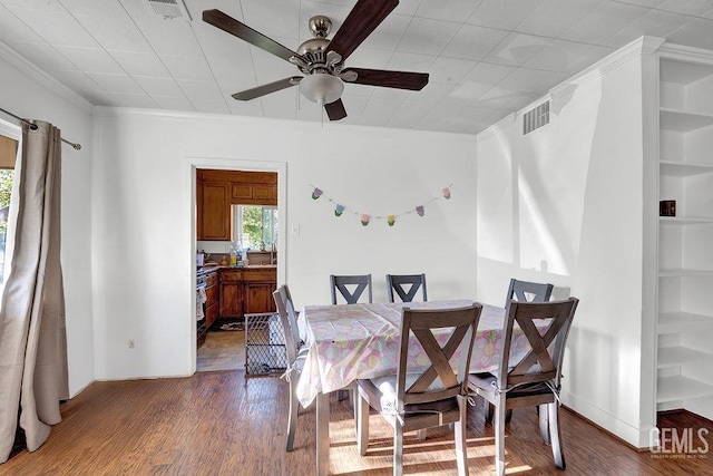 dining space featuring crown molding, wood finished floors, visible vents, and a ceiling fan