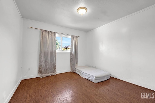 unfurnished room with baseboards, wood finished floors, and ornamental molding