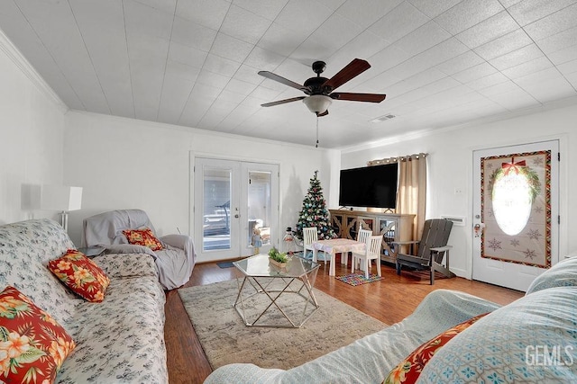 living room with french doors, visible vents, a ceiling fan, wood finished floors, and crown molding
