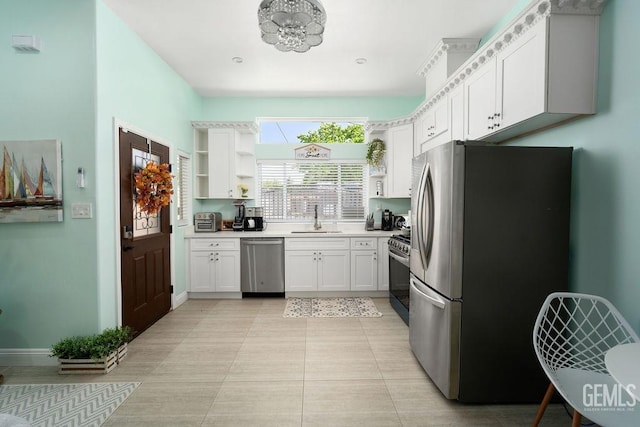 kitchen with appliances with stainless steel finishes, light tile patterned floors, white cabinetry, and sink