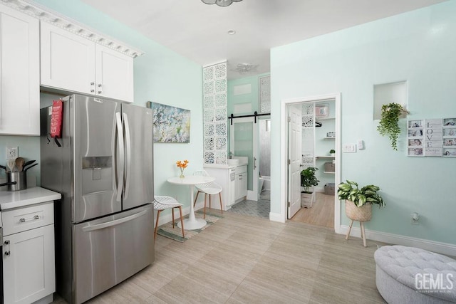 kitchen featuring white cabinetry, a barn door, and stainless steel fridge