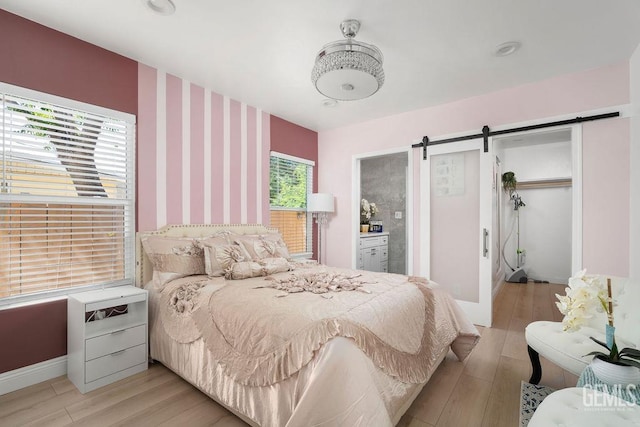 bedroom featuring a barn door and light hardwood / wood-style flooring