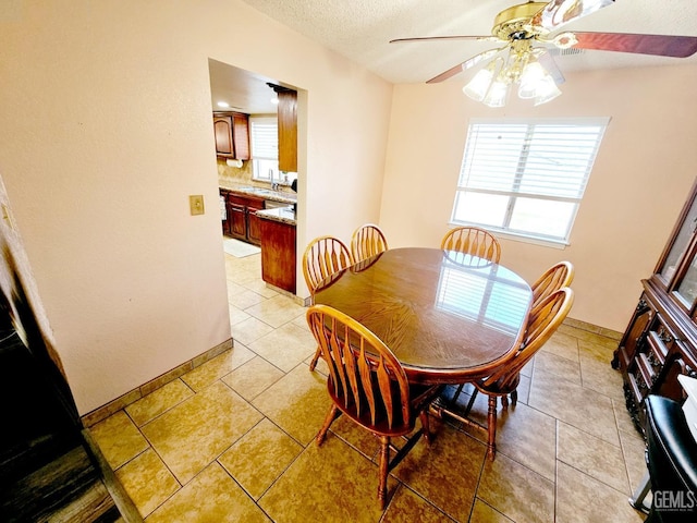 dining space featuring light tile patterned floors, sink, a textured ceiling, and ceiling fan