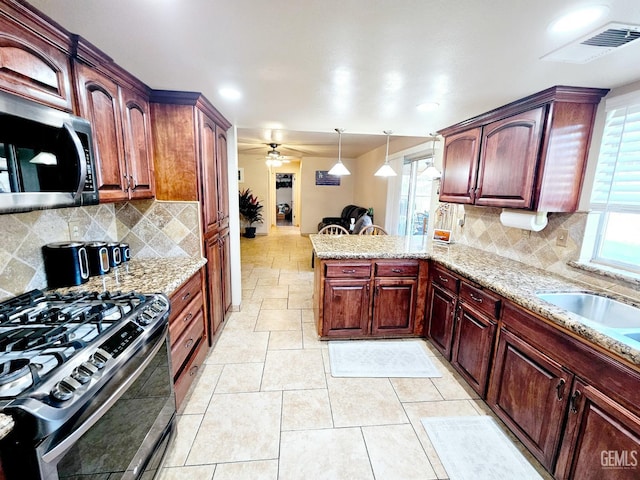 kitchen with sink, appliances with stainless steel finishes, hanging light fixtures, tasteful backsplash, and kitchen peninsula