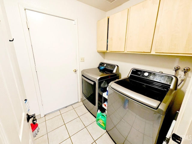 laundry area with separate washer and dryer, light tile patterned floors, and cabinets