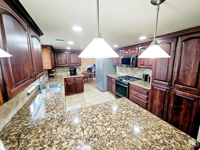 kitchen with sink, decorative light fixtures, backsplash, and appliances with stainless steel finishes