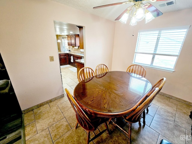 tiled dining room featuring ceiling fan and a textured ceiling