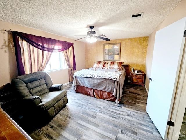 bedroom with wood-type flooring, a textured ceiling, and ceiling fan