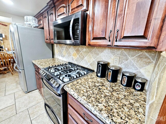 kitchen featuring tasteful backsplash, appliances with stainless steel finishes, light tile patterned floors, and light stone counters