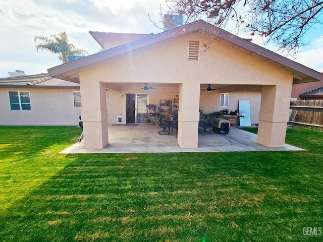 back of property with ceiling fan, a yard, and a patio area