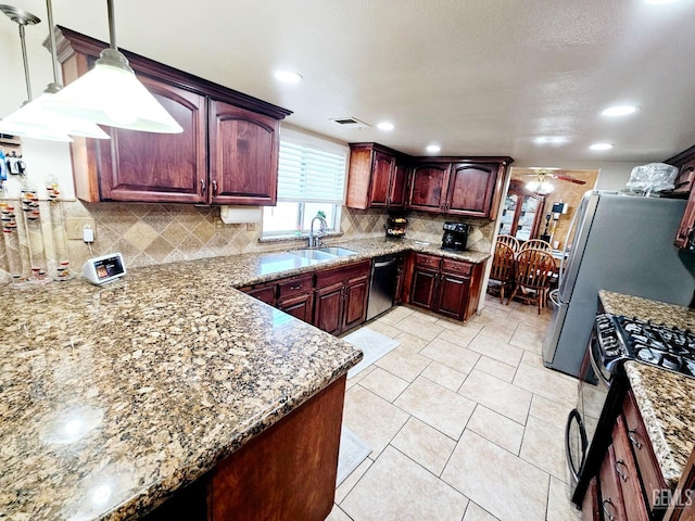 kitchen featuring sink, gas stove, hanging light fixtures, and backsplash