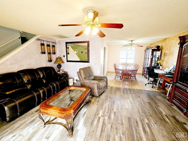 living room featuring ceiling fan, wood-type flooring, and a textured ceiling