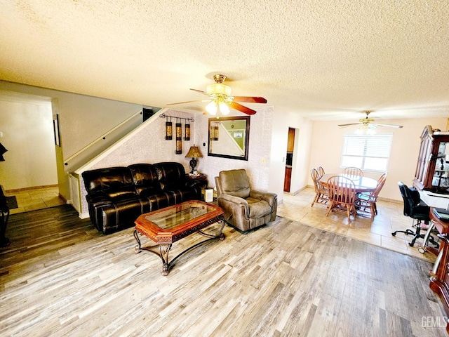 living room with hardwood / wood-style flooring, ceiling fan, and a textured ceiling