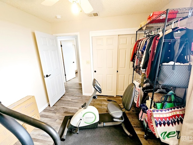 workout area with wood-type flooring, a textured ceiling, and ceiling fan