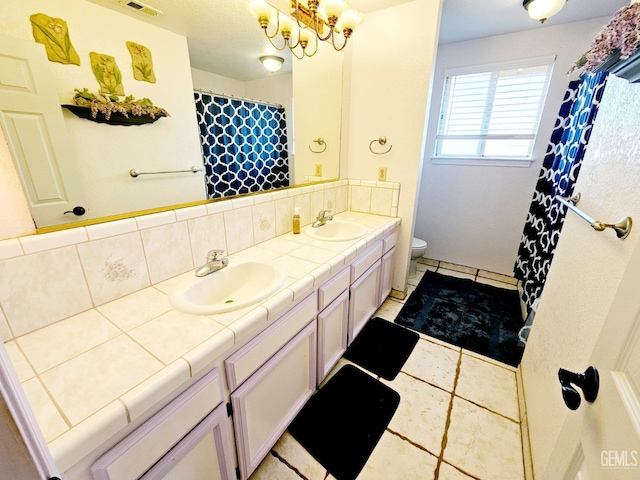 bathroom with tile patterned floors, toilet, tasteful backsplash, vanity, and a notable chandelier