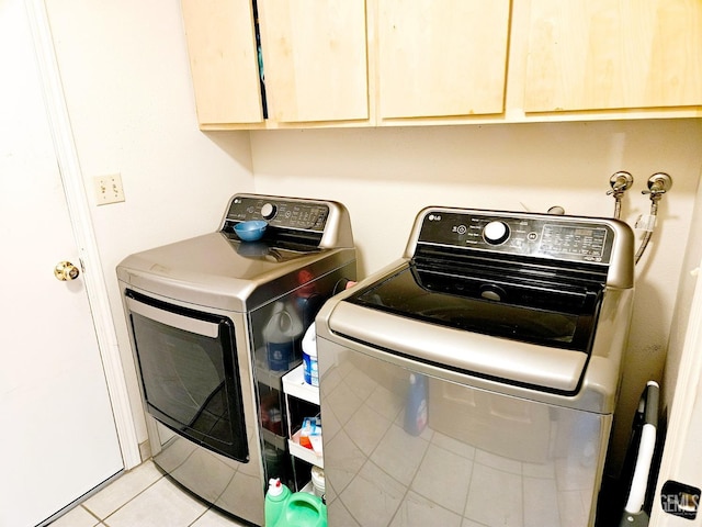 washroom featuring cabinets, light tile patterned floors, and washer and clothes dryer