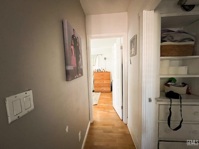 hall featuring light wood-type flooring and baseboards