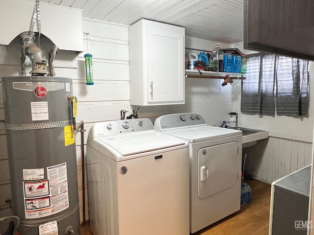 clothes washing area featuring light wood-style flooring, cabinet space, water heater, a sink, and washing machine and dryer