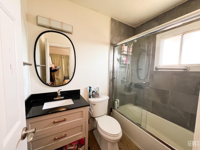 full bath featuring combined bath / shower with glass door, toilet, and vanity