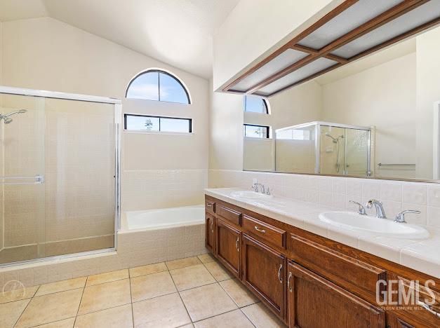 3717 Alcott Dr, Bakersfield, CA 93311 - bathroom featuring a shower stall, a bath, double vanity, vaulted ceiling, and tile patterned floors