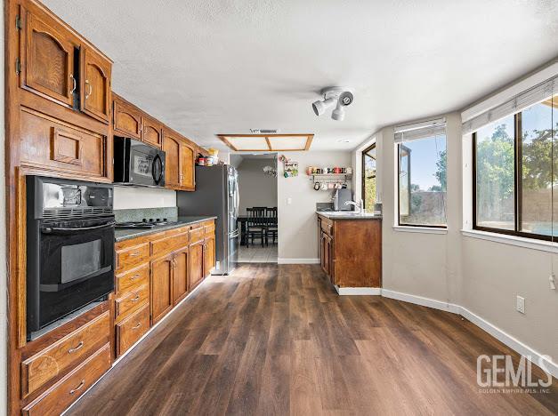 3717 Alcott Dr, Bakersfield, CA 93311 - kitchen featuring black appliances, dark wood-style floors, brown cabinets, and baseboards