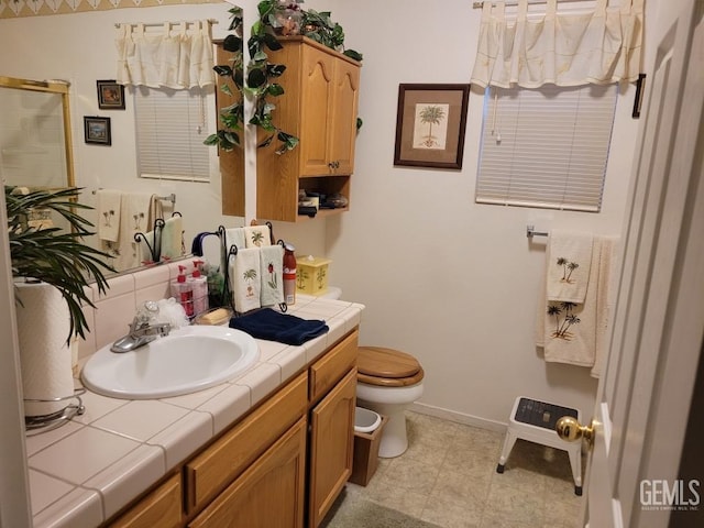 full bathroom with vanity, a shower stall, toilet, and baseboards