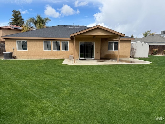 rear view of property with a patio area, stucco siding, a yard, and fence