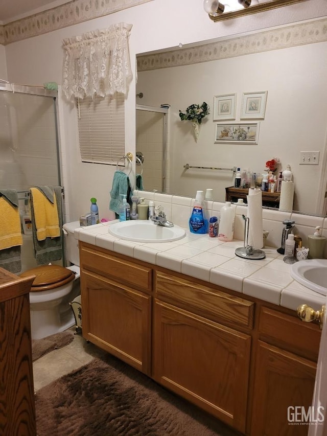 bathroom with tile patterned flooring, toilet, double vanity, a stall shower, and a sink