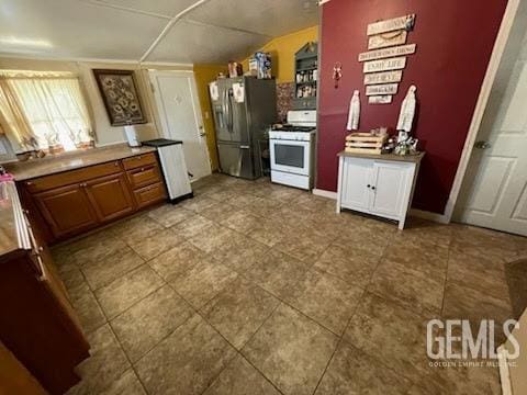 kitchen featuring vaulted ceiling, white gas range, and stainless steel fridge with ice dispenser