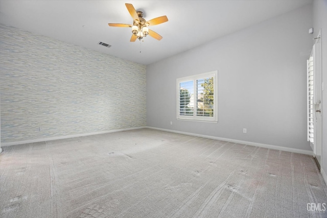 empty room with carpet floors, baseboards, visible vents, and a ceiling fan