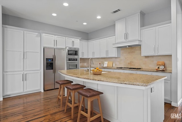 kitchen featuring visible vents, white cabinets, dark wood-type flooring, stainless steel appliances, and under cabinet range hood