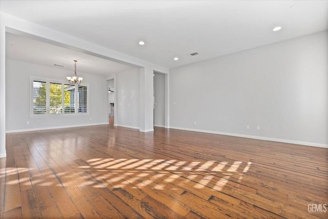 unfurnished living room featuring recessed lighting, visible vents, hardwood / wood-style floors, an inviting chandelier, and baseboards