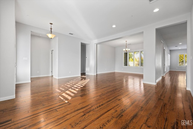 spare room with hardwood / wood-style flooring, recessed lighting, baseboards, and an inviting chandelier