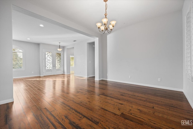 unfurnished living room featuring recessed lighting, baseboards, a notable chandelier, and hardwood / wood-style floors