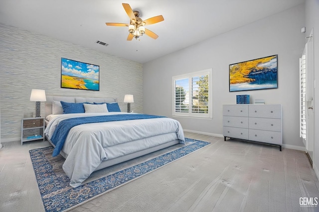 bedroom with visible vents, an accent wall, ceiling fan, baseboards, and wallpapered walls