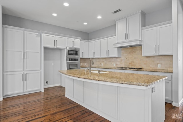 kitchen with stainless steel appliances, a sink, visible vents, white cabinets, and range hood