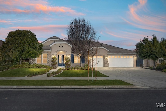 ranch-style house featuring an attached garage, concrete driveway, stone siding, a lawn, and stucco siding