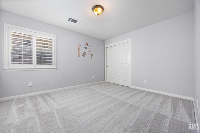 carpeted spare room with visible vents and baseboards