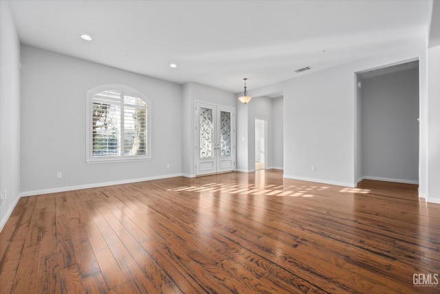 spare room with recessed lighting, wood-type flooring, visible vents, and baseboards