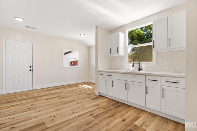 702 Wilson Ave, Bakersfield, CA 93308 - kitchen featuring light wood-type flooring, light countertops, white cabinetry, vaulted ceiling, and recessed lighting