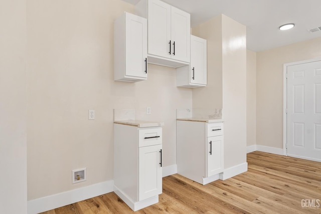 702 Wilson Ave, Bakersfield, CA 93308 - kitchen with light wood-type flooring, light countertops, and white cabinets
