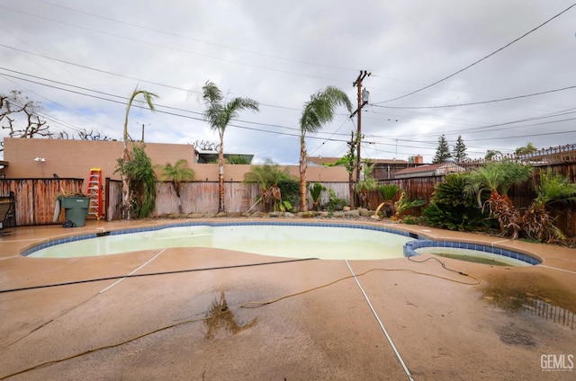 view of pool with a pool with connected hot tub, a fenced backyard, and a patio area